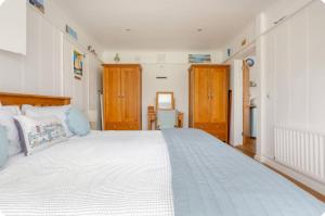 ein Schlafzimmer mit einem großen weißen Bett und Holzschränken in der Unterkunft The Slopes in Whitstable