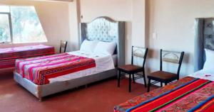 a bedroom with two beds and two chairs at Inti Raymi Lodge in Escallani
