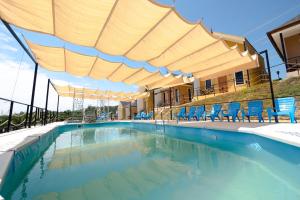 a swimming pool with blue chairs and a large umbrella at Tamu Eco Lenggeng in Lengging