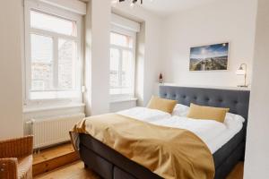 a bedroom with a bed with a blue headboard and two windows at St Jakobshof für Moselurlaub mit Familie in Ediger-Eller