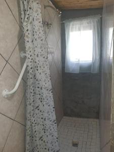 a shower curtain in a bathroom with a window at Chalet 1 Camping Style at Cynthias Country Farmstay Outside bathroom in Hartbeespoort +4 photos