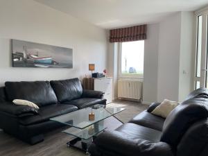 a living room with a black leather couch and a glass table at Apartment 12 in Wilhelmshaven