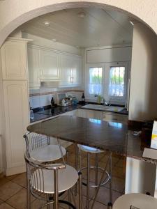 a kitchen with white cabinets and a large island with bar stools at Casa BOWA in Hospitalet de l'Infant