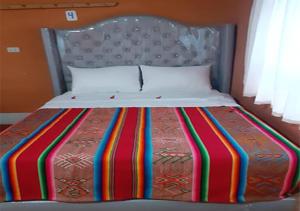 a bed with a colorful striped blanket on it at Inti Raymi Lodge in Escallani +12 photos