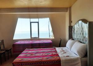 a bedroom with two beds and a large window at Inti Raymi Lodge in Escallani
