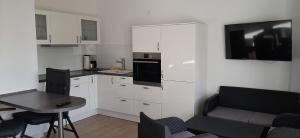 a kitchen with white cabinets and a table and a tv at Apartment 10 in Altefähr am Strelasund in Altefähr
