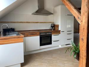 a kitchen with white cabinets and a stove top oven at Ferienwohnung "Turmblick" in Tellingstedt