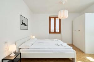 a white bedroom with a bed and a pendant light at Casa Morellato in Riva del Garda