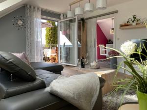 a living room with a black leather couch at Schöne Ferienwohnung in Schauenstein-Hof im Frankenwald mit Loggia 100qm in Schauenstein