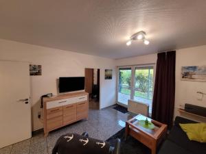 a living room with a flat screen tv and a table at Kleine Auszeit in Dorum-Neufeld