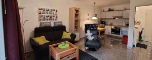 a living room with a black couch and a kitchen at Kleine Auszeit in Dorum-Neufeld