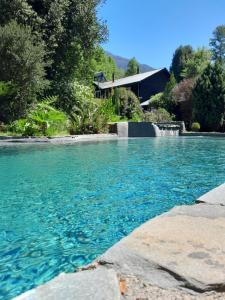 普孔Lodge Tenis Pucon cl的蓝色的海水游泳池,后面有房子