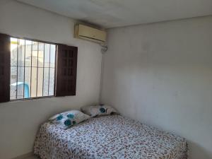 a small bedroom with a bed and a window at Casa de temporada em Tamandaré - PE in Tamandaré