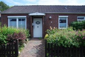 a brick house with a white door and a fence at Jonnys in Hage