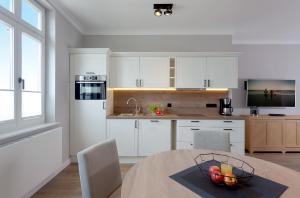 a kitchen with white cabinets and a table with a bowl of fruit at Villa Seeblick Kachliner See in Ahlbeck +14 photos