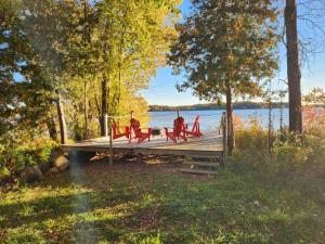 a wooden dock with red chairs on a lake at Stoco Lake Lodge in Tweed