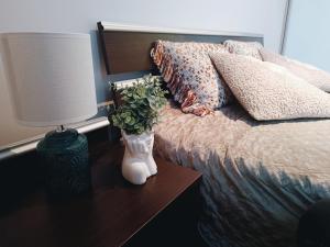a bed with a lamp and a vase with flowers on a table at Apartament Ełk Tuwima 5 in Ełk
