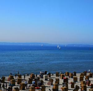 a beach with chairs and the ocean with boats at Tornado in Laboe