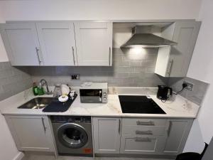 a kitchen with white cabinets and a sink and a stove at Private Cosy Room in Barking