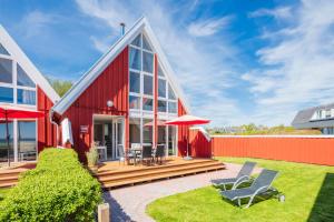 a red house with chairs and an umbrella at Beach 4 in Rettin