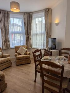 a living room with a table and chairs and a television at SWANAGE WELL PRESENTED 2 BEDROOM APARTMENT CLOSE to BEACH in Swanage