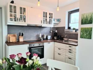 a kitchen with white cabinets and a sink at Ferienwohnung LOUISE in Dreschvitz