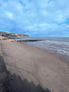 a sandy beach with a pier in the ocean at SWANAGE WELL PRESENTED 2 BEDROOM APARTMENT CLOSE to BEACH in Swanage +19 photos