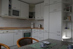 una cucina con mobili bianchi e un tavolo con sedie di Ferienwohnung Auszeit a Geeste