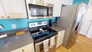 a kitchen with a stove and a refrigerator at Salty Sanctuary in Folly Beach