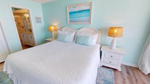 a bedroom with a white bed with blue walls and two lamps at Salty Sanctuary in Folly Beach