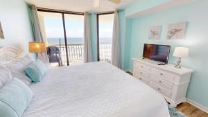 a bedroom with a bed with a television and a balcony at Salty Sanctuary in Folly Beach