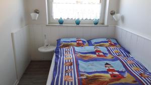 a small bedroom with a bed with a lighthouse quilt at Butjadinger Friesenstube in Butjadingen