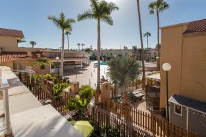 a fence in front of a pool with palm trees at Bungalow Chill Terrace in Maspalomas & Pool in San Bartolomé de Tirajana