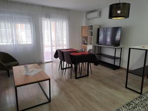 a living room with a table and chairs and a television at Chloe Apartments TRG in Benidorm