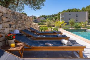 einen Pool mit Holzbänken neben einer Steinmauer in der Unterkunft Villa Praska with private 28,5 sqm pool, 3 en-suite bedrooms, Sauna, 1km to Beach in Podstrana