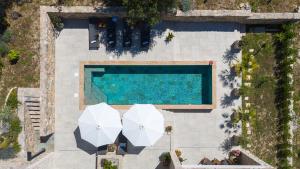 einen Blick über einen Pool mit zwei Sonnenschirmen in der Unterkunft Villa Praska with private 28,5 sqm pool, 3 en-suite bedrooms, Sauna, 1km to Beach in Podstrana + 45 Fotos