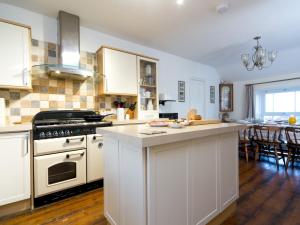 莫伊尔弗雷Tyn Lon, Moelfre, A Traditional Welsh Home By The Coast - Pass the Keys的厨房配有白色橱柜和炉灶烤箱