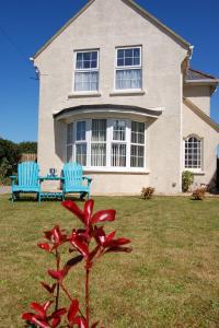 a house with two blue chairs and a red flower at Angorfa family holiday home with games room in Tywyn