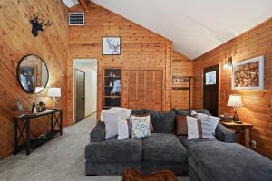 a living room with a gray couch and wooden walls at Basecamp in La Pine