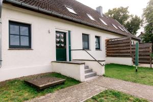 a white house with a green door and stairs at kleines Landdomiziel in Damerow +3 photos