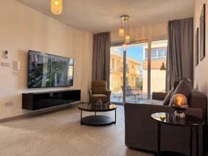 a living room with a couch and a flat screen tv at City Hall Suites in Limassol