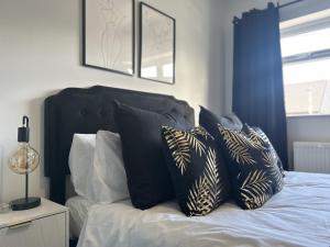 a bed with black and white pillows on it at The Cotswold Cornerstone in Billingham