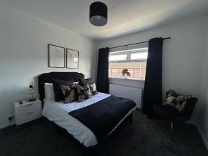 a bedroom with a bed and a window and a chair at The Cotswold Cornerstone in Billingham