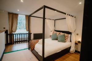 a bedroom with a canopy bed with white sheets and pillows at Slateford House 1770 Luxury Aparthotel by The House of Danu in Edinburgh