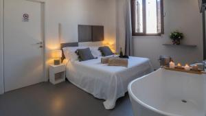 a white bedroom with a bed and a bath tub at New Dimora Valmar in Polignano a Mare