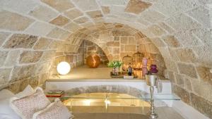 a room with a stone archway with a glass table at New Dimora Valmar in Polignano a Mare