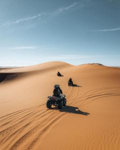 a group of people riding on a quad bike in the desert at Merzouga Glossy Camp in Merzouga
