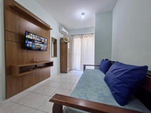 ein Schlafzimmer mit einem Bett und einem Fernseher an der Wand in der Unterkunft Apartamento completo Condomínio Caribe Ubatuba in Ubatuba