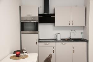 a kitchen with white cabinets and a table with a wine glass at Casa Kronengarten Nr 5 in Hilden