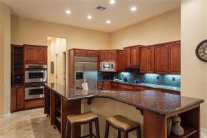 a kitchen with wooden cabinets and a large island with bar stools at Caledonia Dreamin in Anthem
